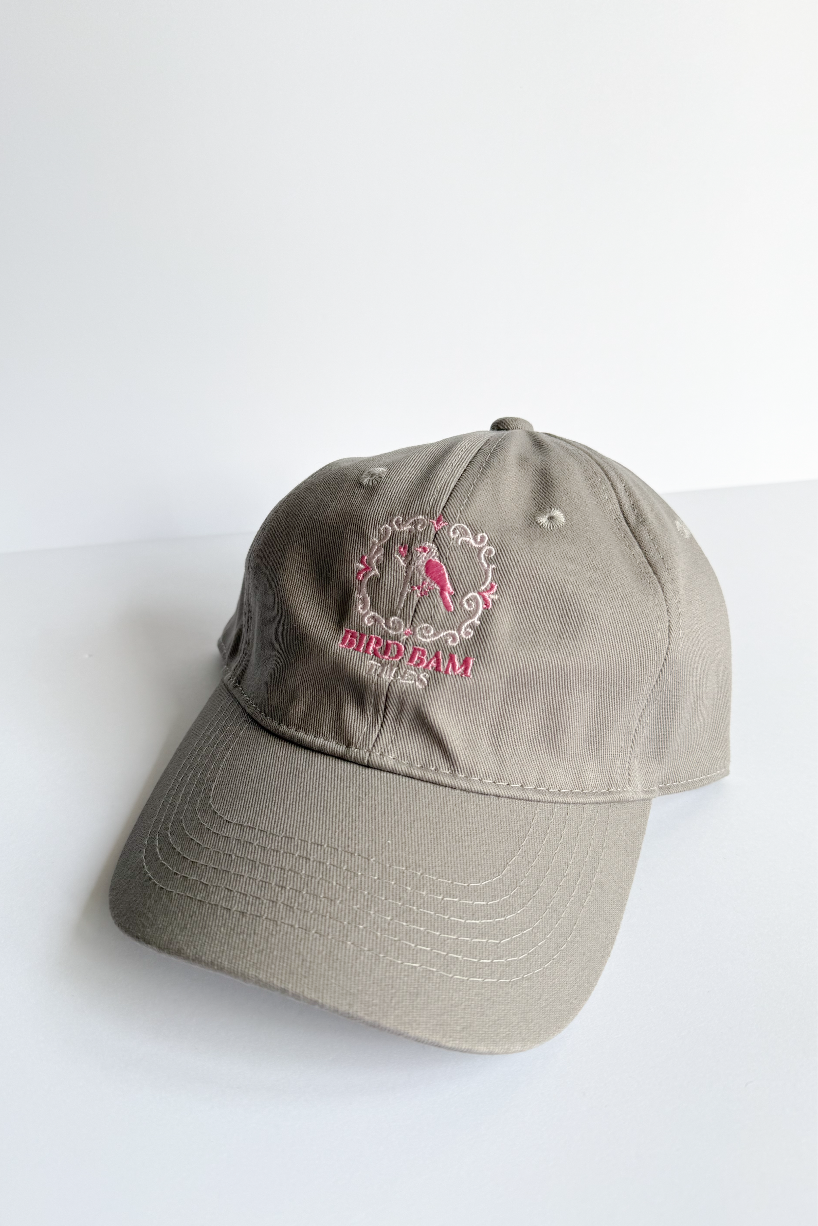 Gray beige baseball hat with multi-toned pink Bird Bam Tiles embroidered logo on a white background