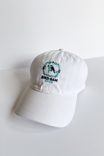 White baseball hat embroidered with 2-toned blue Bird Bam Tiles logo on a white background