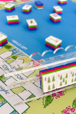 Close-up of a scalloped acrylic rack with colorful tiles on a mahjong mat background
