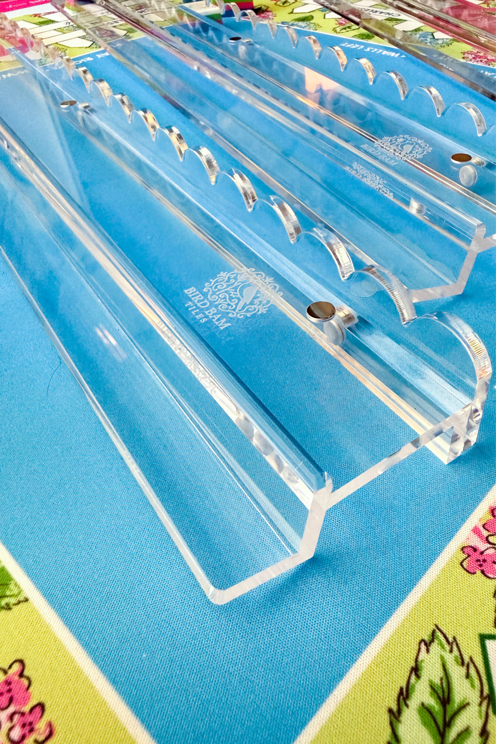 Clear acrylic racks and pushers with etched Bird Bam Tiles logo on colorful mahjong mat background