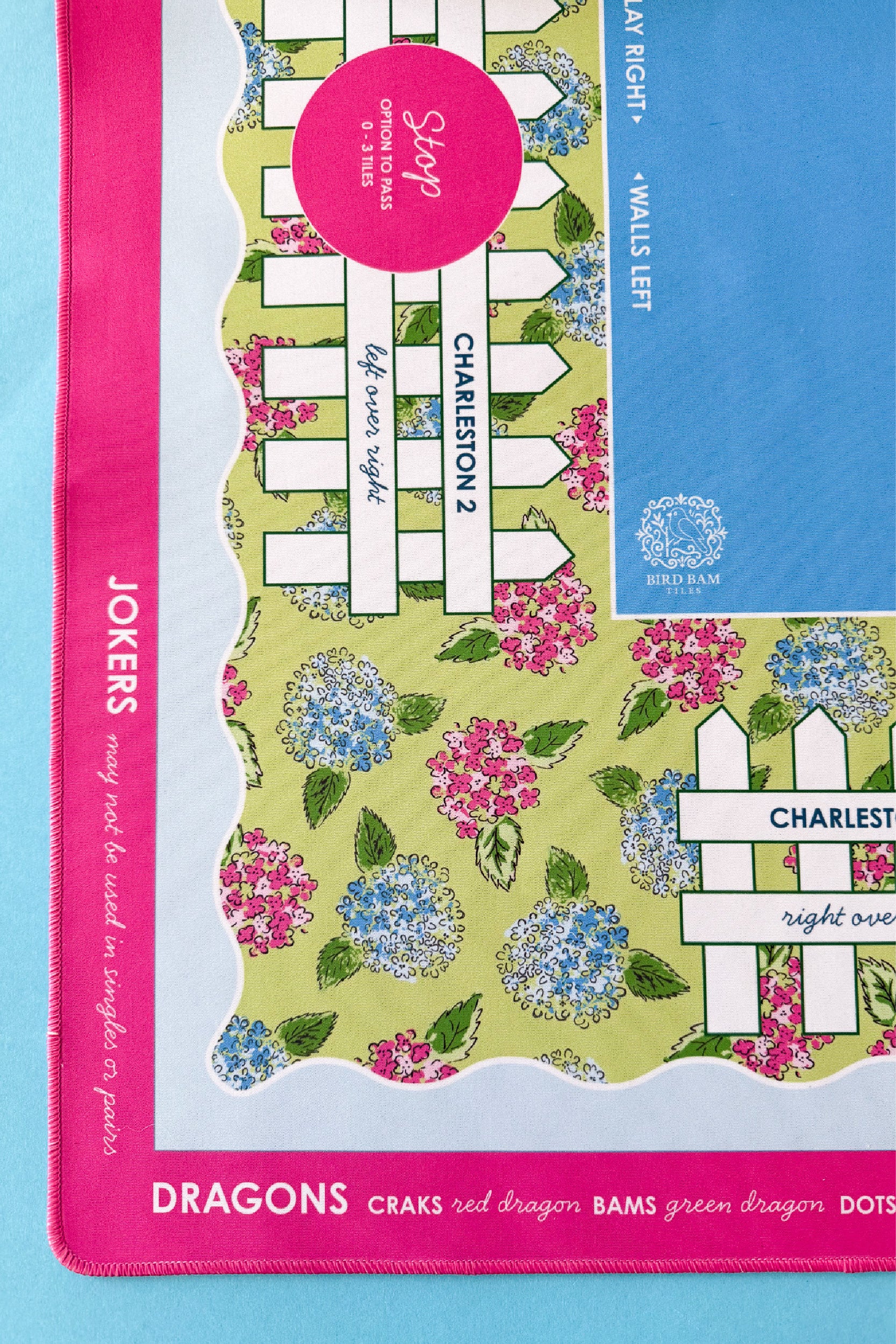 Details of a colorful mahjong mat with floral design and pink border on a blue background